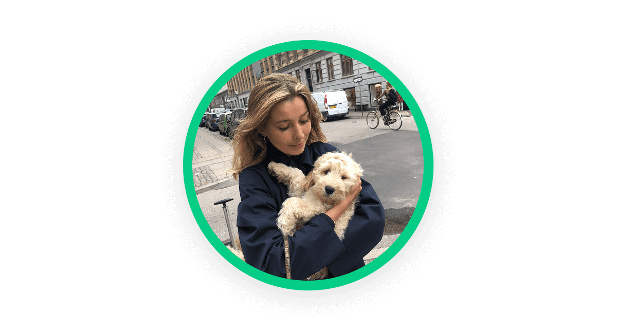 A circular image showing a photo of a woman holding her dog in her arms and looking down at it