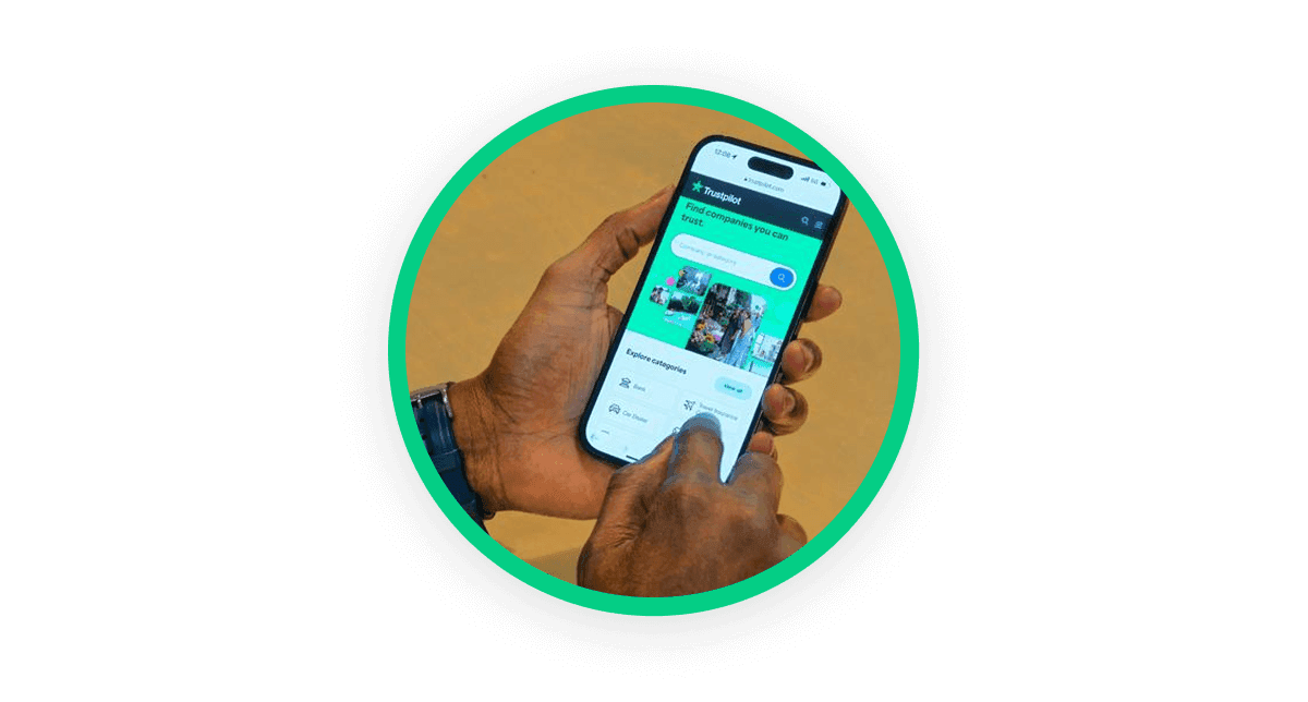 A circular image showing a close up of someone's hand, holding a smartphone that is displaying the Trustpilot website
